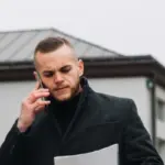 Mlad čovek razgovara na telefonu i gleda u papir